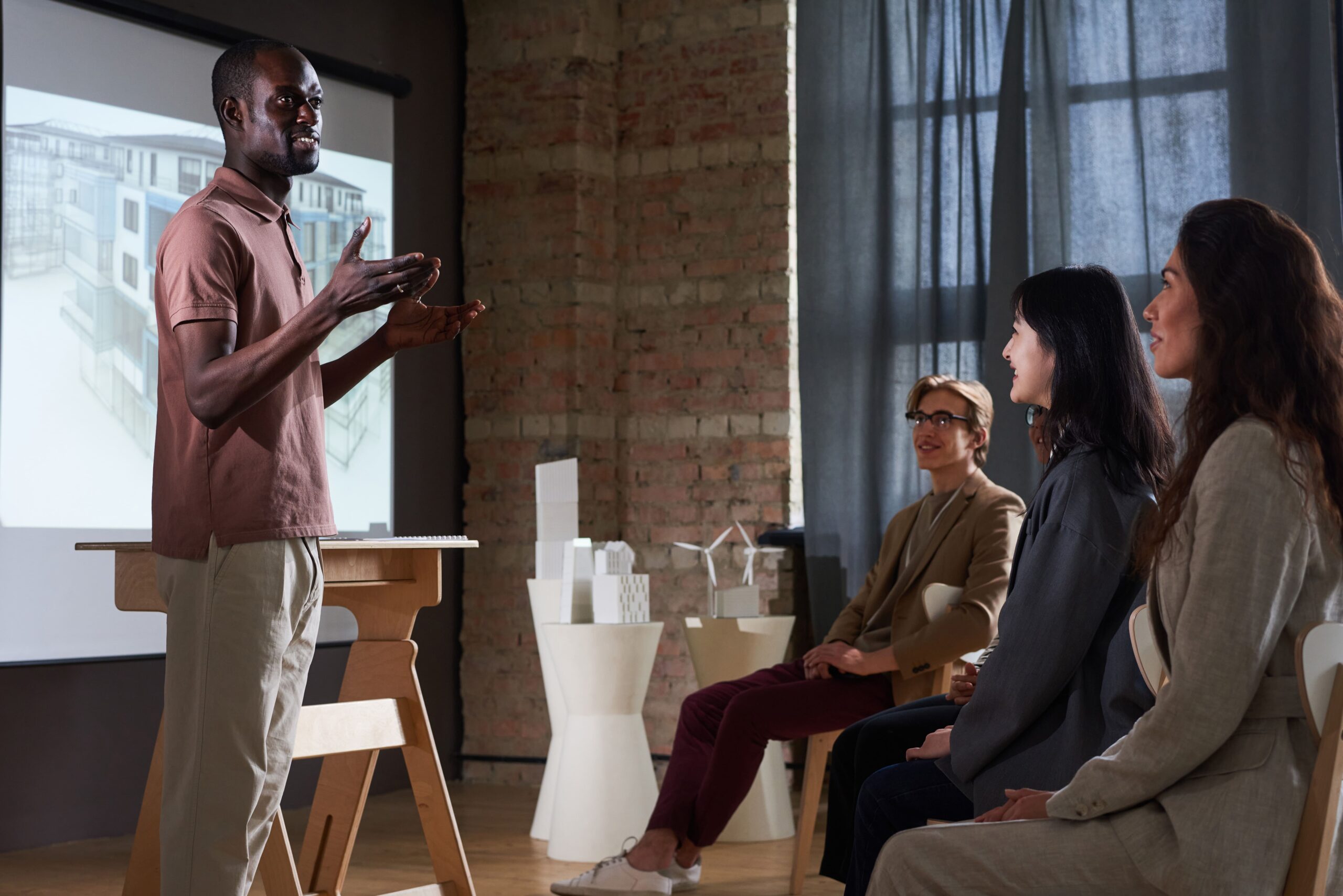 Professional speaker presenting a complex idea to a group of business professionals with visuals on screen.
