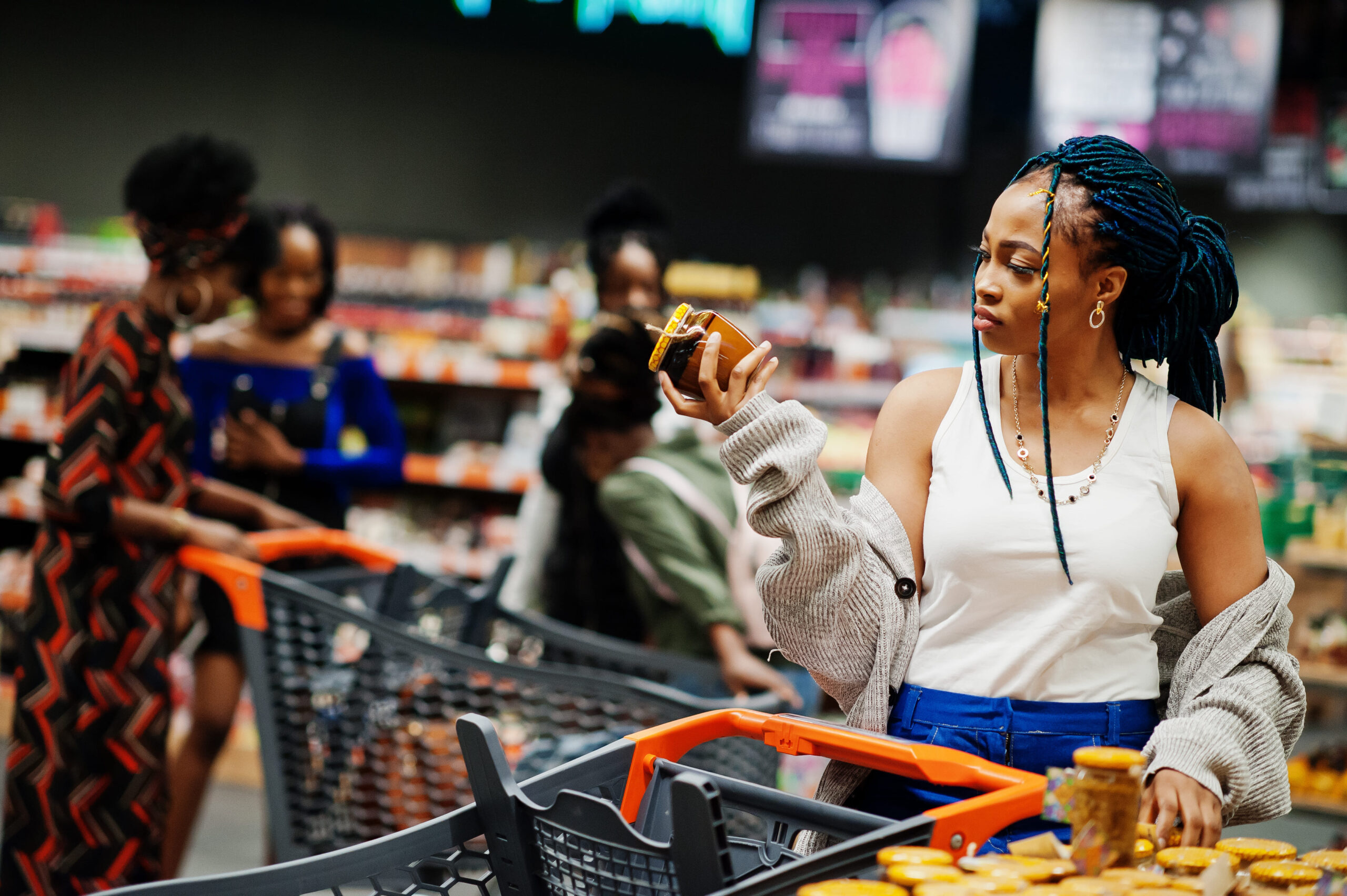 Woman in a grocery store comparing product labels, representing buyer evaluation and hesitation caused by unclear information.
