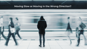 Person standing still on a subway platform while commuters blur past, symbolizing slow movement versus moving in the wrong direction in business strategy.