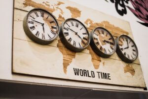 World time zone clocks on a wall representing global collaboration and time zone differences in creative production