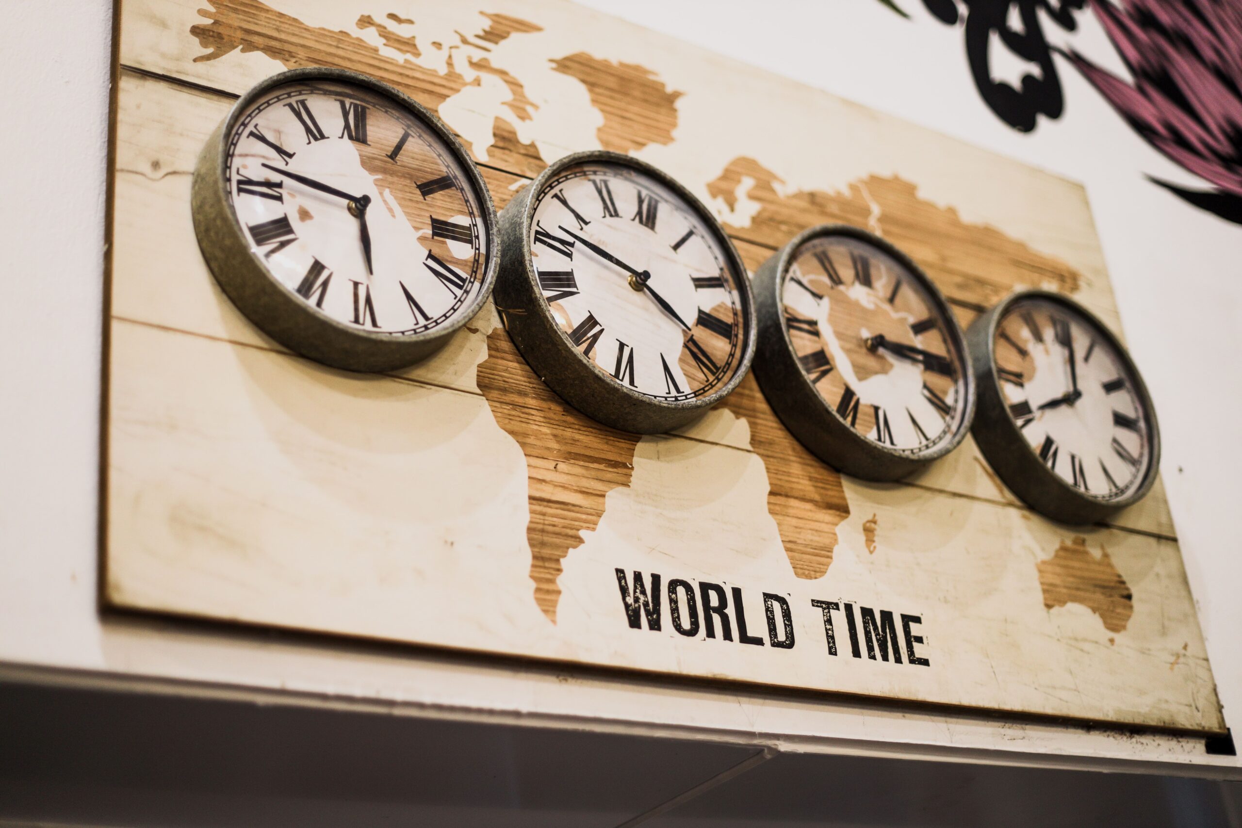 World time zone clocks on a wall representing global collaboration and time zone differences in creative production